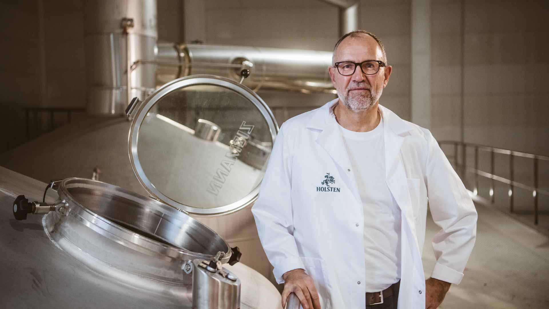 Mitarbeiter Olaf steht stolz an einem Braukessel in der Holsten Brauerei
