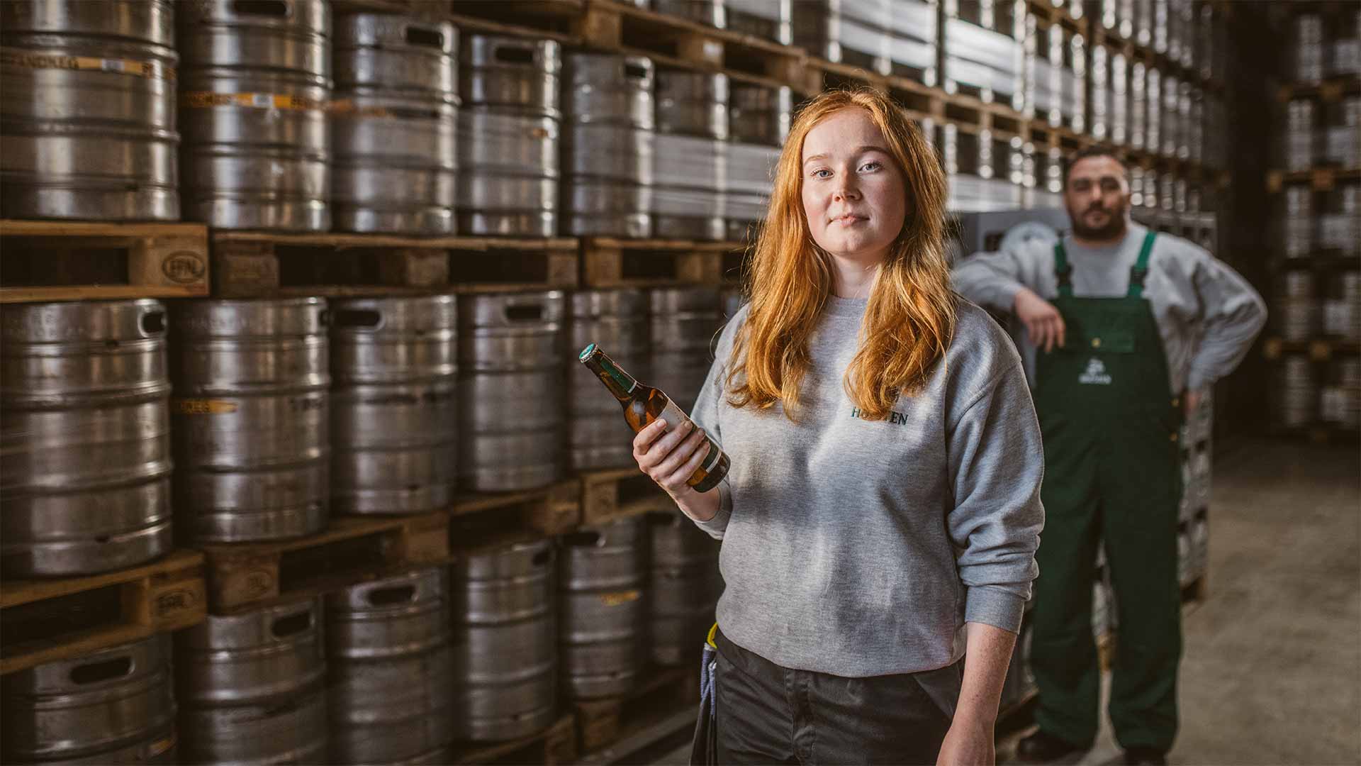 Abgefüllte Holsten Fässer stehen abholbereit hinter Mitarbeitern im Lager