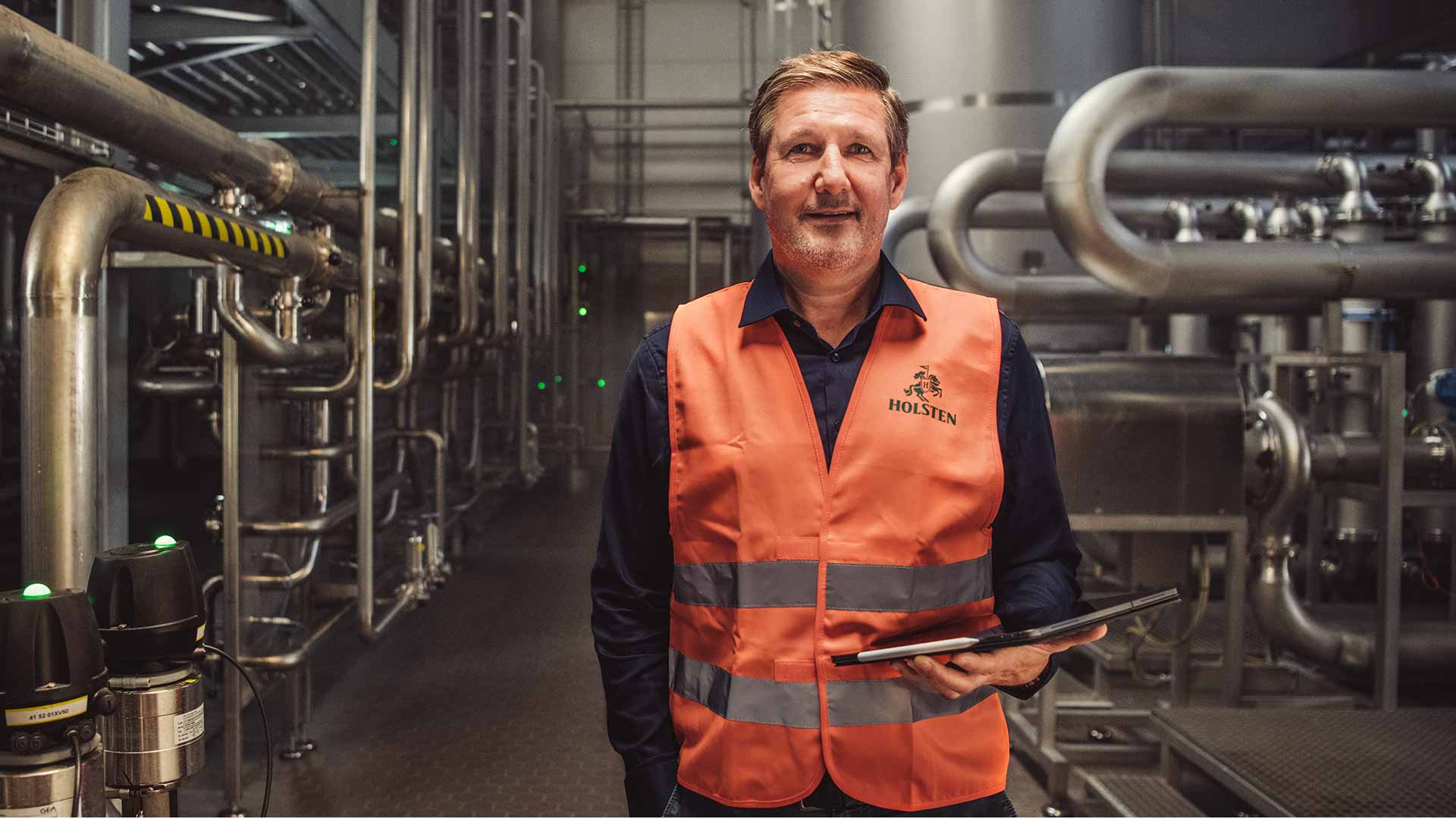 Holsten Key Account Manager Ralf steht stolz in Arbeitskleidung in der Brauerei